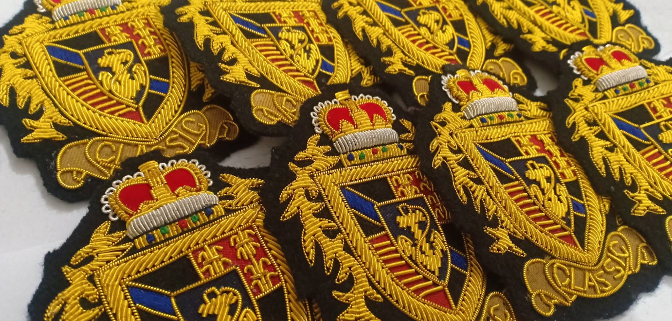 Stapel handgeborduurde blazer-badges met familiewapen, kroon en eikenbladmotief in goud-, zilver- en zijdedraad op zwart vilt
